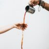 person pouring liquid on drinking glass